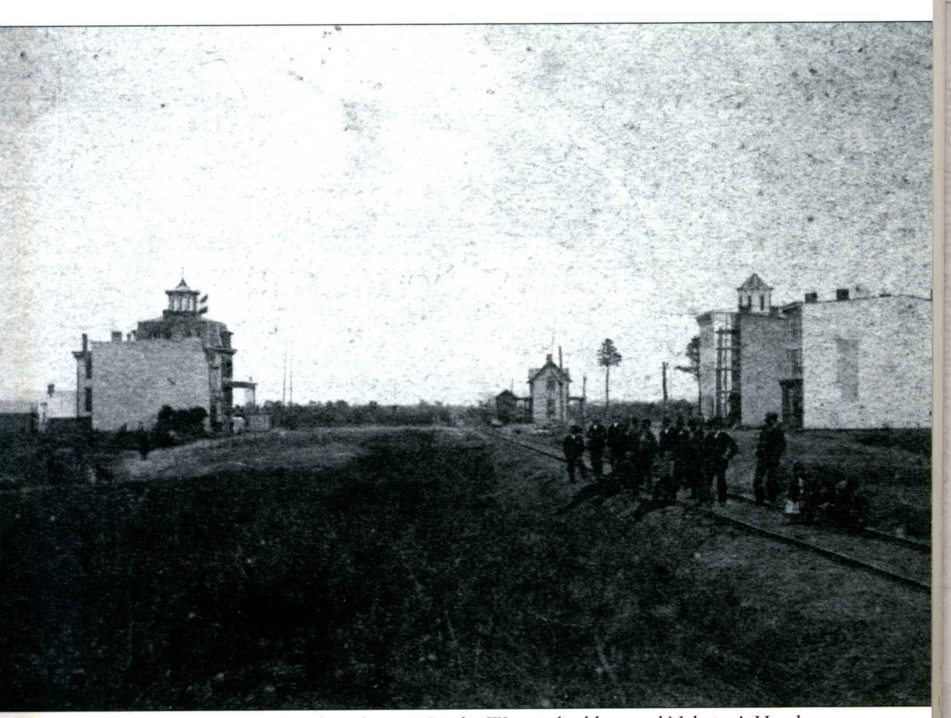 Lindenhurst, 1871, showing the Bank Building & Gleste's Hotel on the right, train depot in the middle & Wagner Building & Nehring's Hotel on the left.